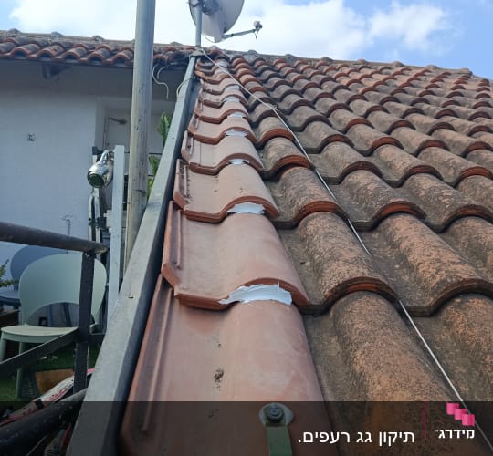 גג רעפים עם אנטנה ולוויין על רקע שמיים כחולים